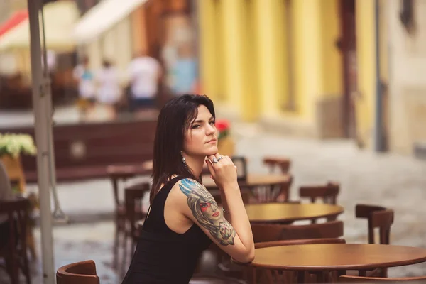 Une belle jeune fille est assise dans un café. À l'extérieur — Photo