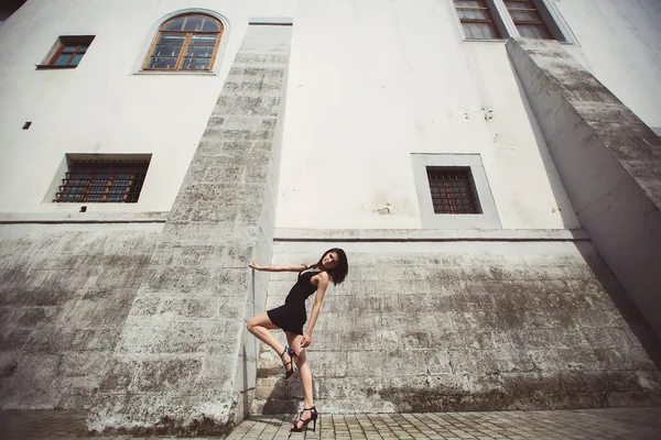 Hermosa chica en un vestido negro se encuentra cerca de la estructura arquitectónica — Foto de Stock