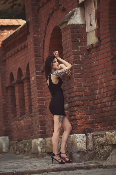 Hermosa chica en un vestido negro se encuentra cerca de la estructura arquitectónica — Foto de Stock