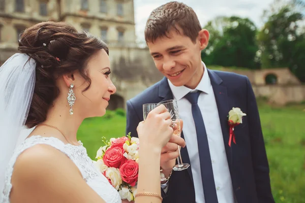 Junge Brautpaare klirren mit Gläsern und genießen romantische Momente, um — Stockfoto