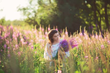 Lavanta bir alanda günbatımı üzerinde tutan güzel genç kadın. Yani
