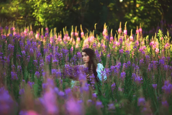 Junge Frau in einem Lavendelfeld mit Blumen in den Händen — Stockfoto