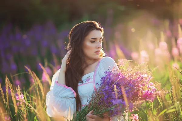 Belle jeune fille, heureuse, tenant la lavande dans un champ sur les soleils — Photo