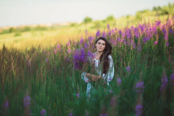 Девушка с цветами в руке, мягко улыбаясь — стоковое фото