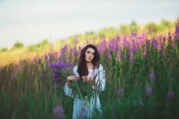 Girl holding flowers in hand, smiling gently — Stock Photo, Image