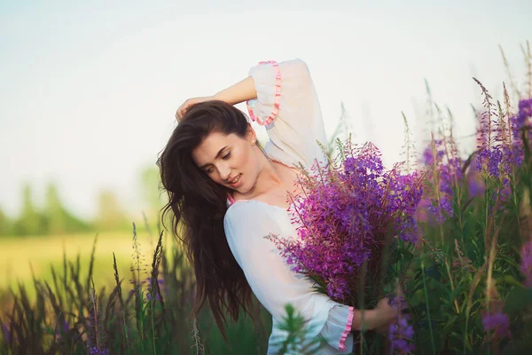 Счастливая девушка в поле, позирует, красивые длинные каштановые волосы — стоковое фото