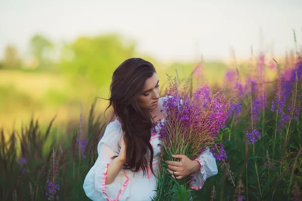 Fille dans une longue robe blanche, caressant les cheveux longs, debout dans une fi — Photo