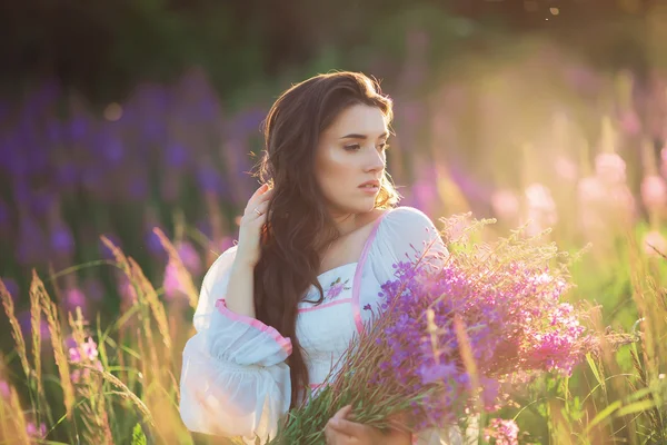 Mooie jonge meisje, gelukkig, lavendel houden in een veld op suns — Stockfoto
