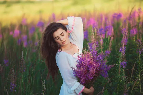 A woman with her eyes closed, posing in a field of lavender, hol — Stock Photo, Image