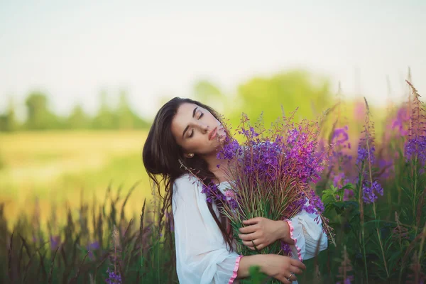 Una donna con gli occhi chiusi, in posa in un campo di lavanda, alcool — Foto Stock