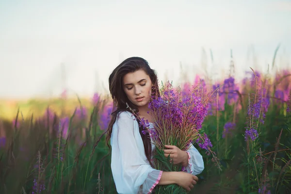 Una donna con gli occhi chiusi, in posa in un campo di lavanda, alcool — Foto Stock