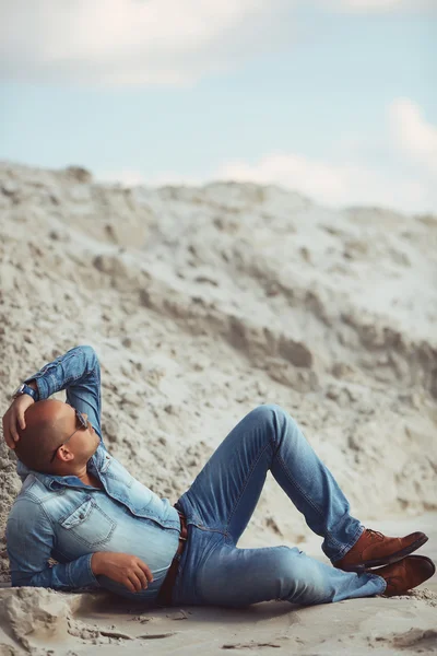 Chico joven en ropa vaquera acostado en la arena en Turquía — Foto de Stock