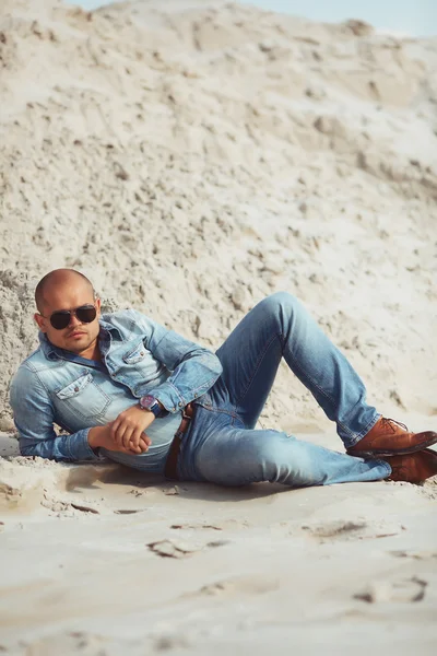 El hombre a la moda de estilo acostado en la arena — Foto de Stock