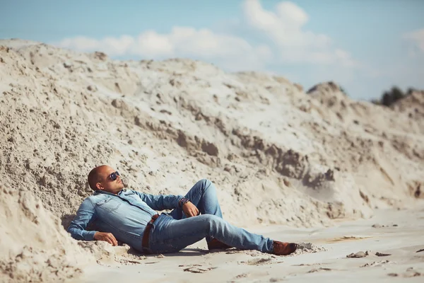 Hombre bronceado por el sol acostado en la arena — Foto de Stock