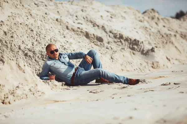 Hombre bronceado por el sol acostado en la arena — Foto de Stock