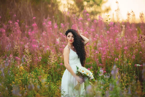 Mooie jonge vrouw in paarse bloemen buiten — Stockfoto