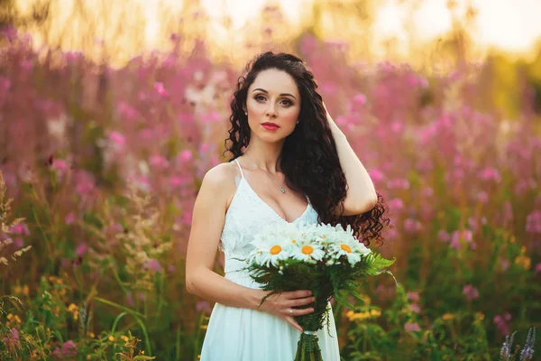 Une jeune fille avec un grand bouquet de fleurs blanches dans un champ à — Photo