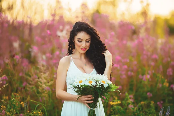 Uma jovem com um grande buquê de flores brancas em um campo em — Fotografia de Stock