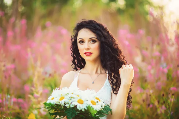 Ein junges Mädchen mit einem großen Strauß weißer Blumen auf einem Feld bei — Stockfoto
