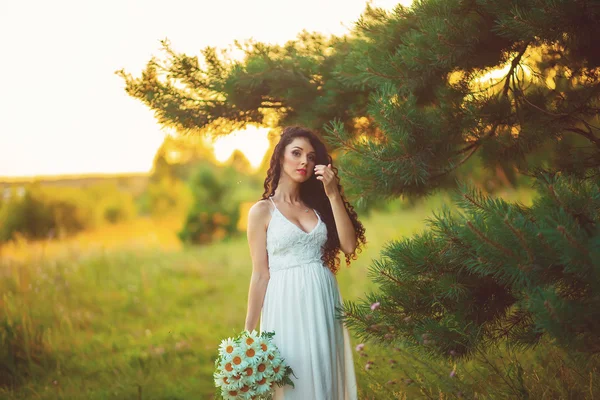 밖에 있는 자주색 꽃을 든 아름다운 젊은 여자 — 스톡 사진