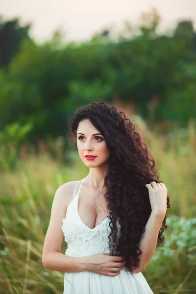 Bela jovem mulher em um campo com um buquê nas mãos — Fotografia de Stock