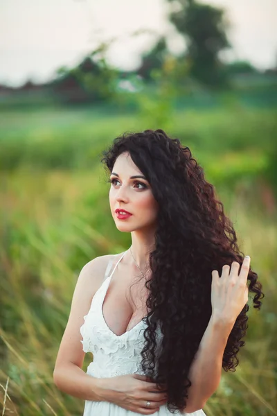 Bela jovem em um campo em vestido branco tem lindo lon — Fotografia de Stock