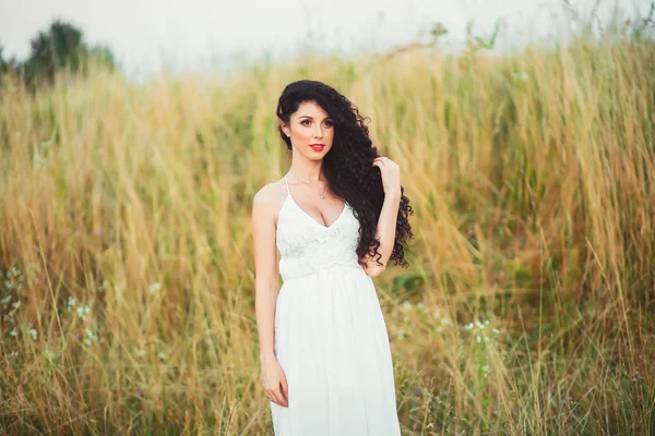 Piękna dziewczyna w polu w białej sukni ma piękne lon — Zdjęcie stockowe