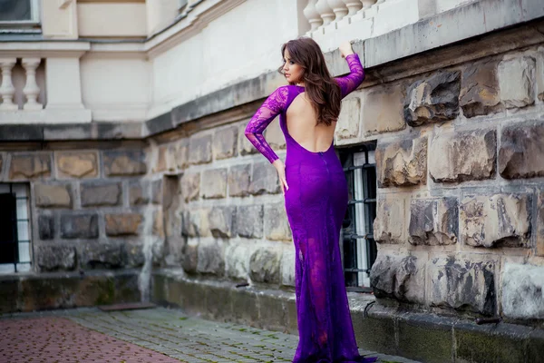 Beautiful girl in the purple dress leaned on the wall — Stock Photo, Image