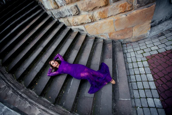 Jovem menina bonita no vestido roxo olhos fechados azuis deitado — Fotografia de Stock