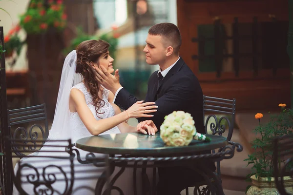 Mariée et marié dans un café en plein air, se regardant émail — Photo