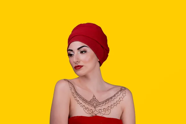 Chica árabe bronceada en una bufanda roja, tatuaje de henna. amarillo aislado —  Fotos de Stock