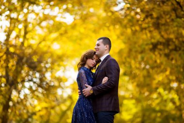 Beautiful newlywed couple having a stroll in park at autumn