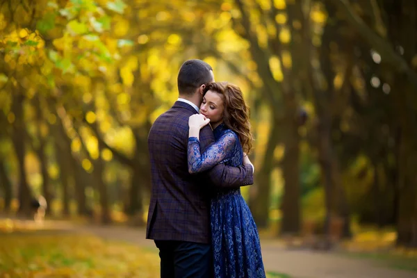 Happy young couple embrace in a park in autumn — Stock Photo, Image