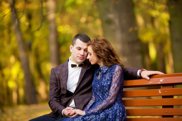 Groom and Bride sitting on bench in a park. wedding dress. — Stok fotoğraf