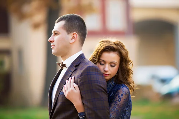 Beautiful bride embracing groom from back at park — Stock Photo, Image