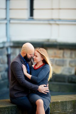 Parmaklığa, tarihi bir binada oturan aşk, şık giyinmiş, genç bir çift