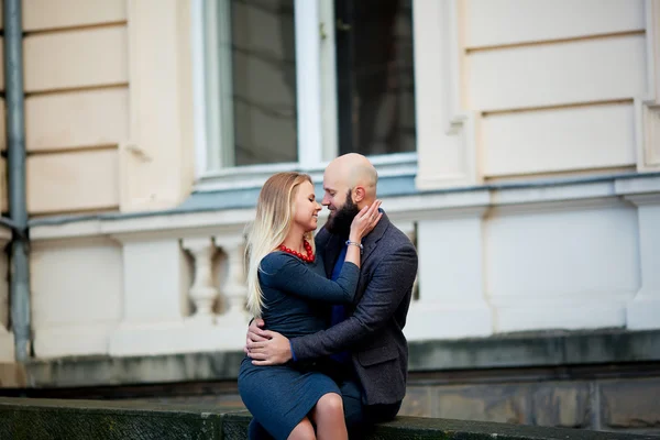 Una bella coppia emotiva elegante di giovane donna e uomo anziano con lunga barba nera che abbraccia seduti uno accanto all'altro — Foto Stock