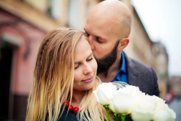 Une photo d'un couple heureux le jour de la Saint Valentin avec des fleurs, l'embrasse — Photo