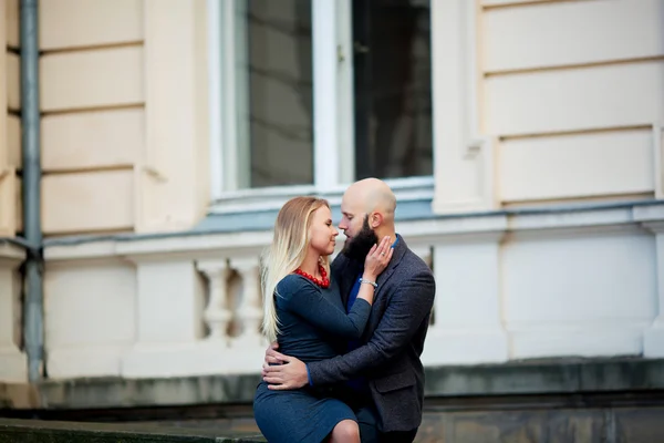Een mooie stijlvolle emotionele paar van jonge vrouw en senior man met lange zwarte baard omarmen zitten dicht bij elkaar — Stockfoto