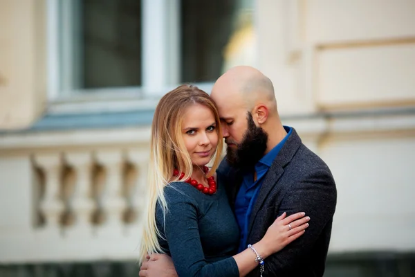 Adorable pareja en un día soleado, de pie cerca de la pared abrazarse —  Fotos de Stock