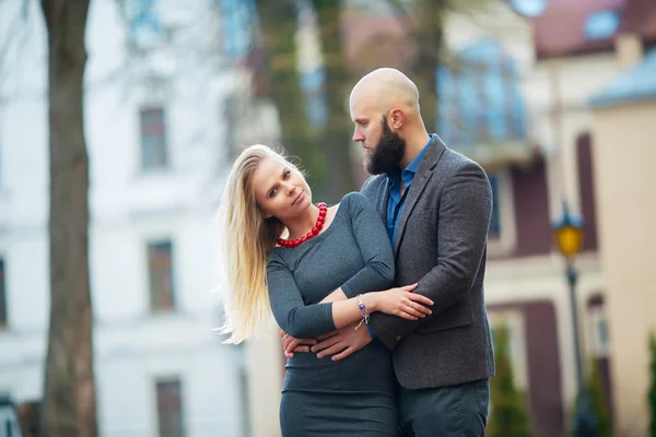 Krásná dívka objímá chlap, stylově oblečená, plešatý muž s vousy — Stock fotografie