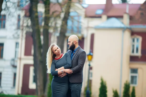 Vacker flicka omfamnar den killen, stilfullt klädd, skallig man med ett skägg — Stockfoto