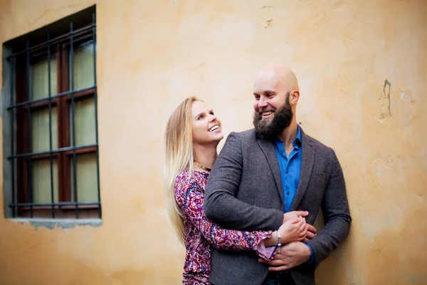 Heureux couple souriant, debout près du mur dans les bras — Photo