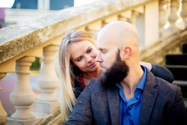 Ett ungt par i kärlek, stilfullt klädd, sitter på trappan, mot en historisk byggnad — Stockfoto