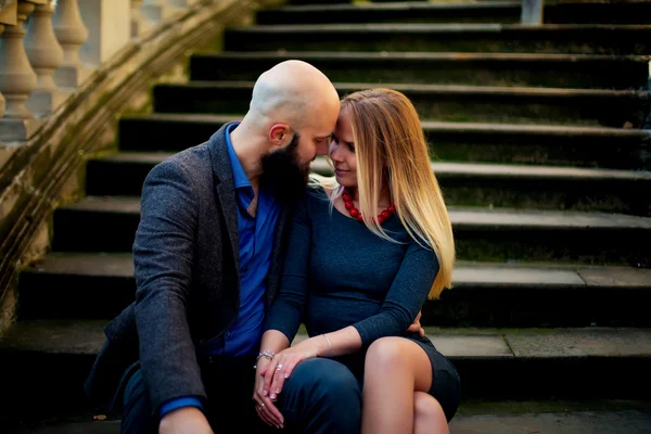 Casal feliz no amor uns com os outros, Um belo casal elegante de mulher jovem e homem sênior com longa barba preta abraçando perto uns dos outros ao ar livre na rua de outono em escadas dia ensolarado — Fotografia de Stock