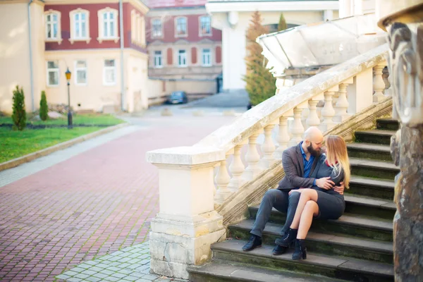 Mosolygós barna menyasszony séta a régi lépcsőn jóképű vőlegény egy kapu, a háttérben — Stock Fotó