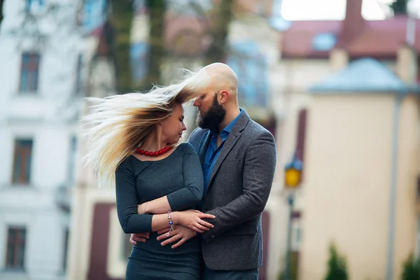 Gelukkige paar verliefd op elkaar, een mooie stijlvolle paar jonge vrouw en senior man met lange zwarte baard omarmen dicht bij elkaar in het najaar straat op trap zonnige dag buiten — Stockfoto