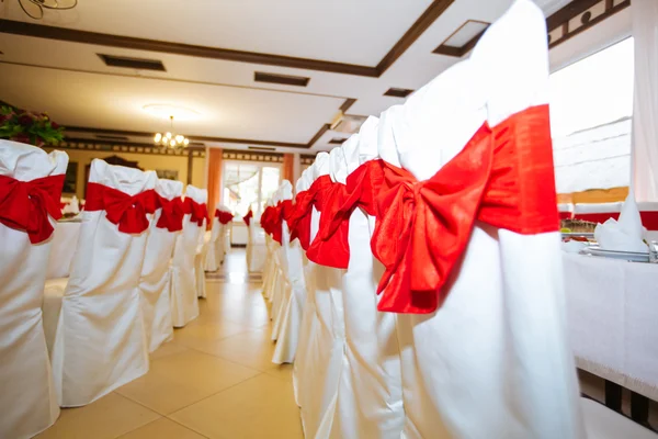 Chaises de mariage en rangée décorées avec un ruban de couleur dorée . — Photo