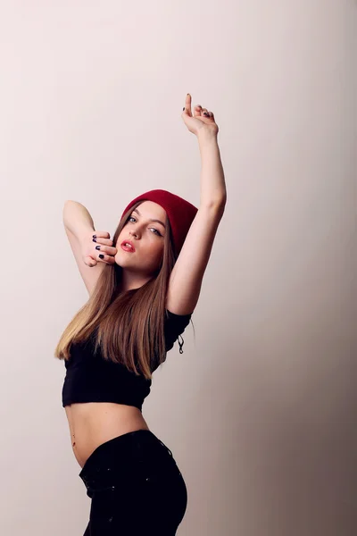 Chica feliz de pie en un estudio sobre fondo beige, gorra en la cabeza, posando modelo, labios rojos — Foto de Stock