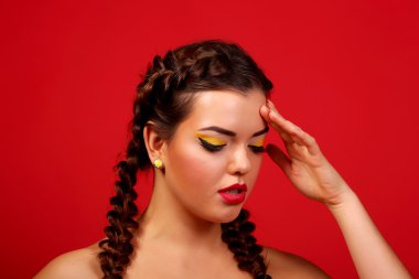 Headache - young woman holding his head on a red background